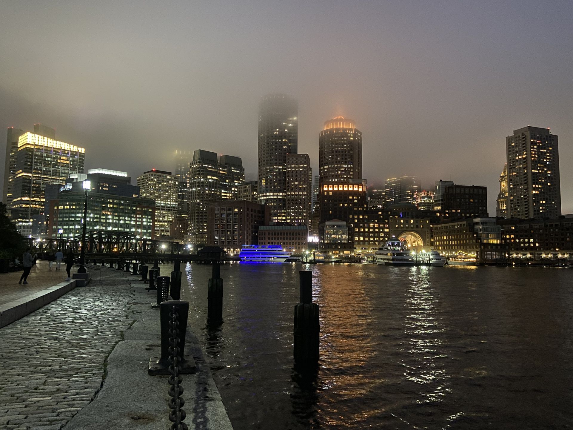The Boston skyline at night, dissolving into fog over the harbor