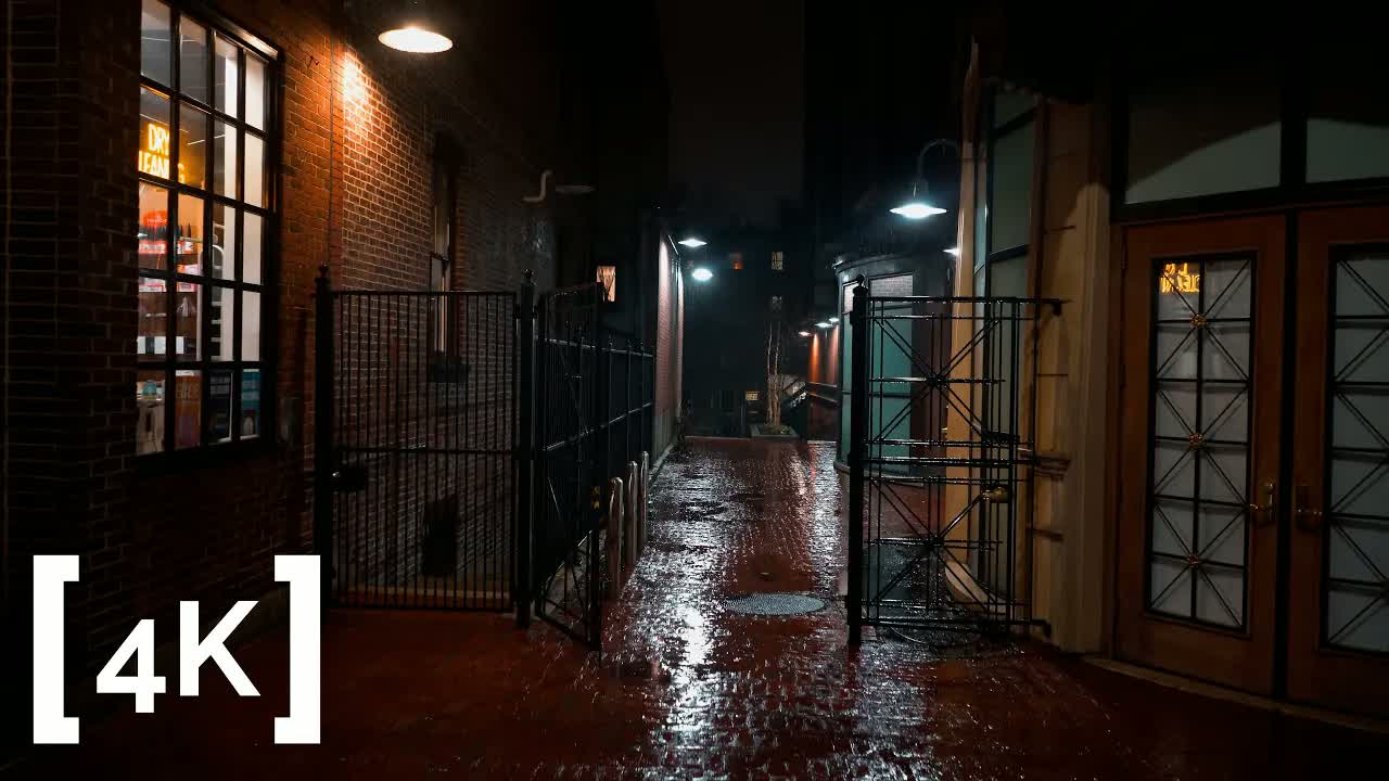 Harvard Square, Cambridge at night in rain: open iron gates and rain-slick brick lit by storefront windows
