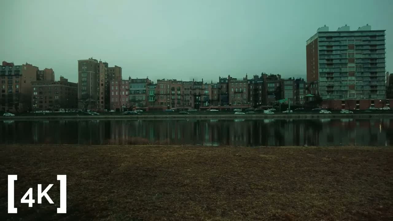 Charles River Esplanade at early morning in fog: a row of brick townhouses reflected in the flat gray river.