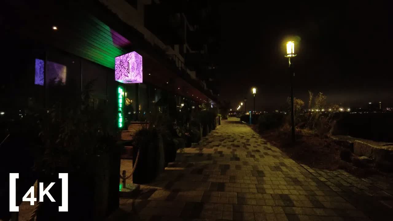 Boston Seaport at night in fog: a lamppost lighting brick pavers along the empty harborwalk