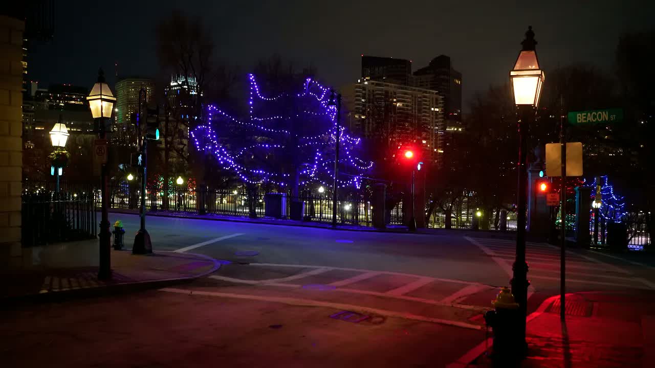Beacon Hill, Boston at midnight in winter: a lit gas lamp beside the Beacon Street sign, purple lights strung through bare trees.