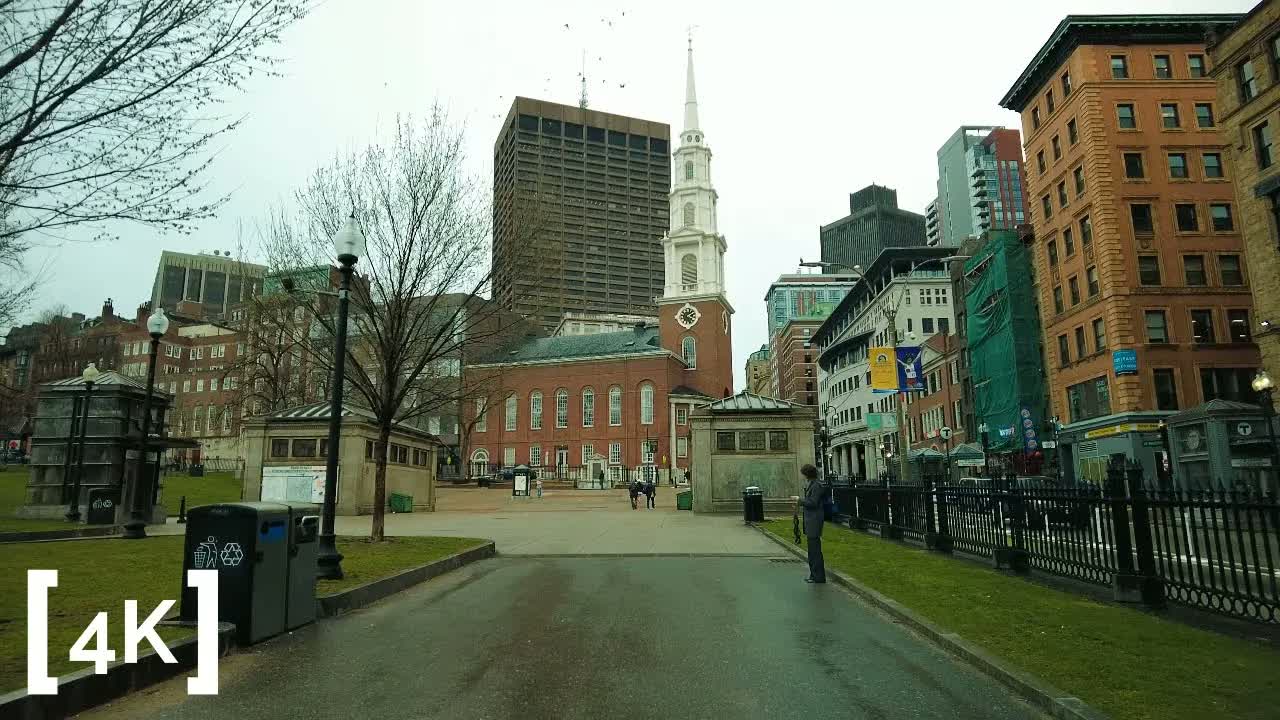 Boston Common at afternoon after rain: a white church steeple above wet asphalt paths and the Common's granite subway kiosks.