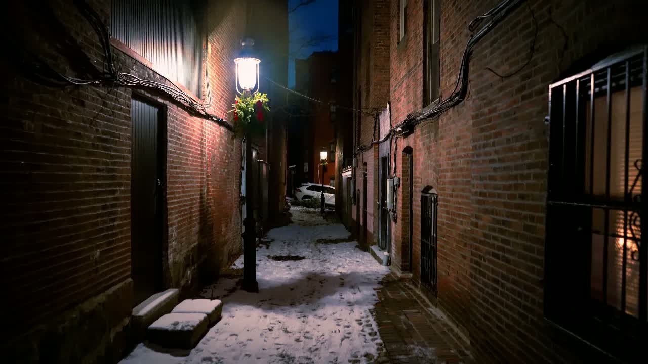 Beacon Hill at midnight in winter snow: a lantern hung with holiday greenery above a footprinted snowy alleyway.