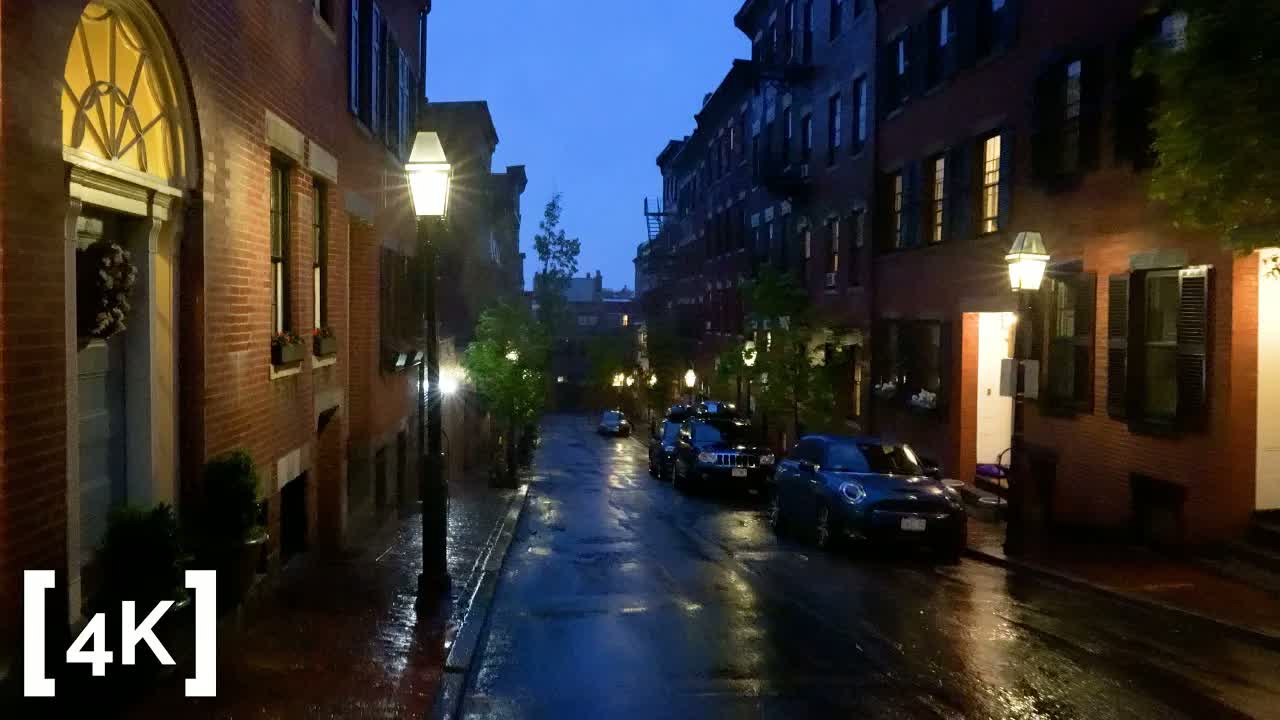 Beacon Hill at dusk in heavy rain: lit gas lamps above a wet street of brick row houses.