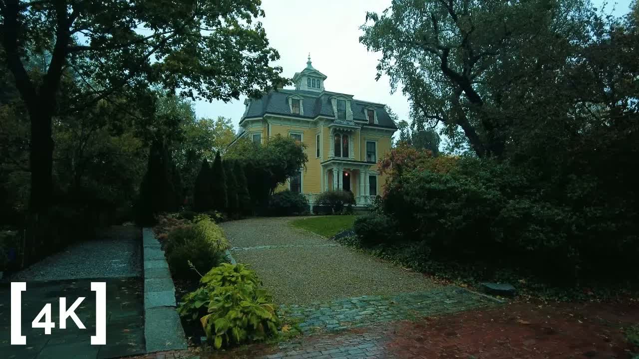 Avon Hill, Cambridge at evening in autumn rain: a yellow mansard-roofed house with a cupola behind wet trees and a gravel drive.