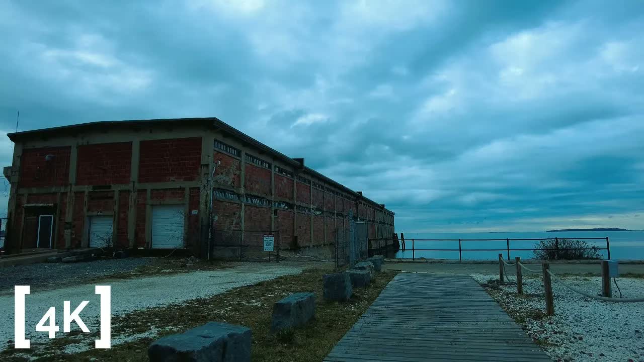 Plymouth at sunset after rain: a wooden boardwalk running past an old brick building toward Plymouth Bay