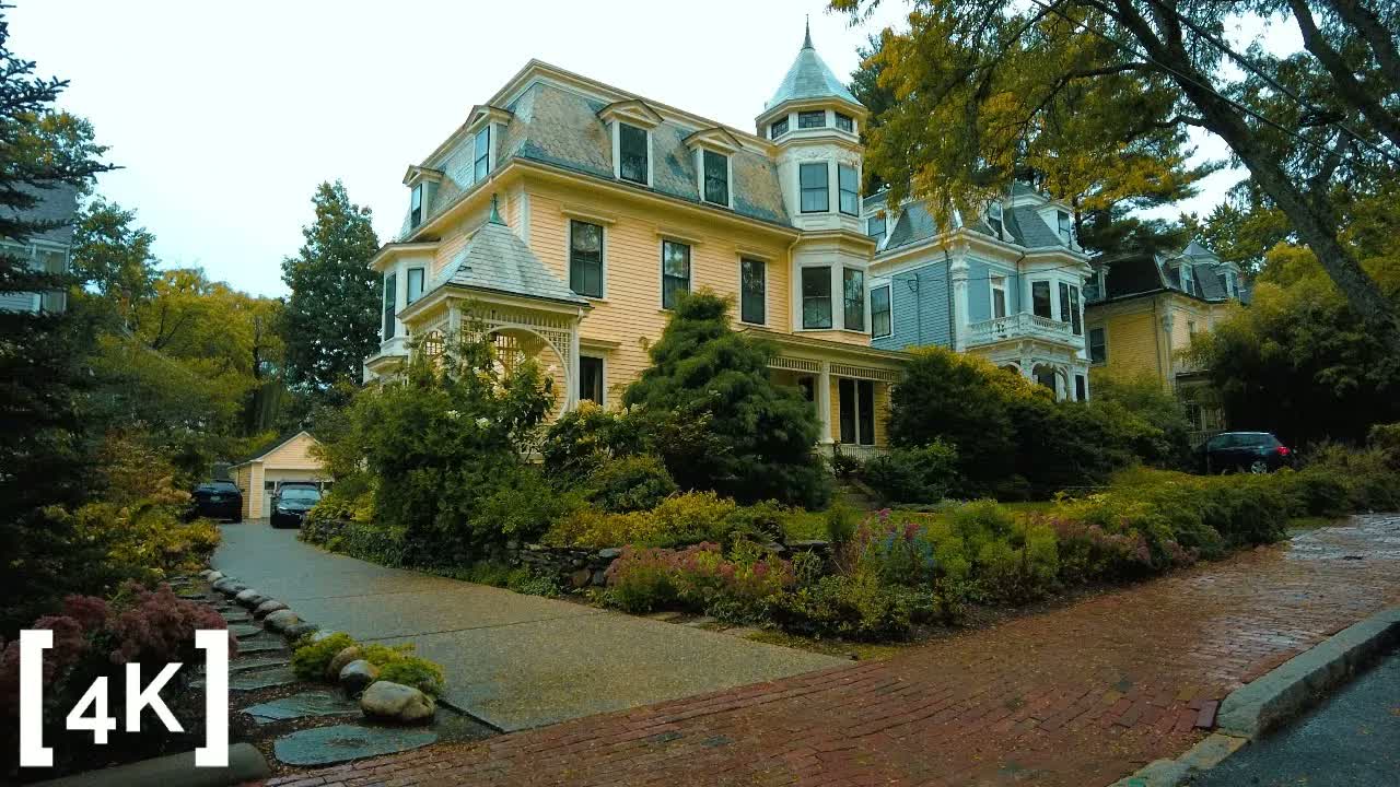 Cambridge, Massachusetts on a rainy day: a yellow Victorian house with a corner turret above a wet red-brick street.