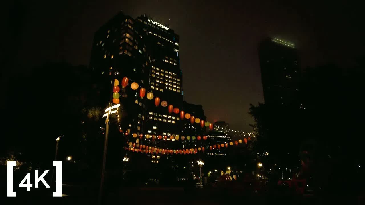 Boston Chinatown at night in fog: strings of red and orange paper lanterns crossing beneath a lit office tower.